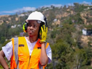 construction site worker pressing her ear protector to her ear