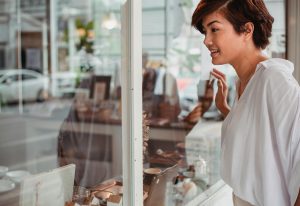 smiling woman peeking through a storefront window