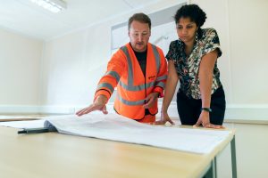 contractor and professionally dressed woman discussing a blueprint